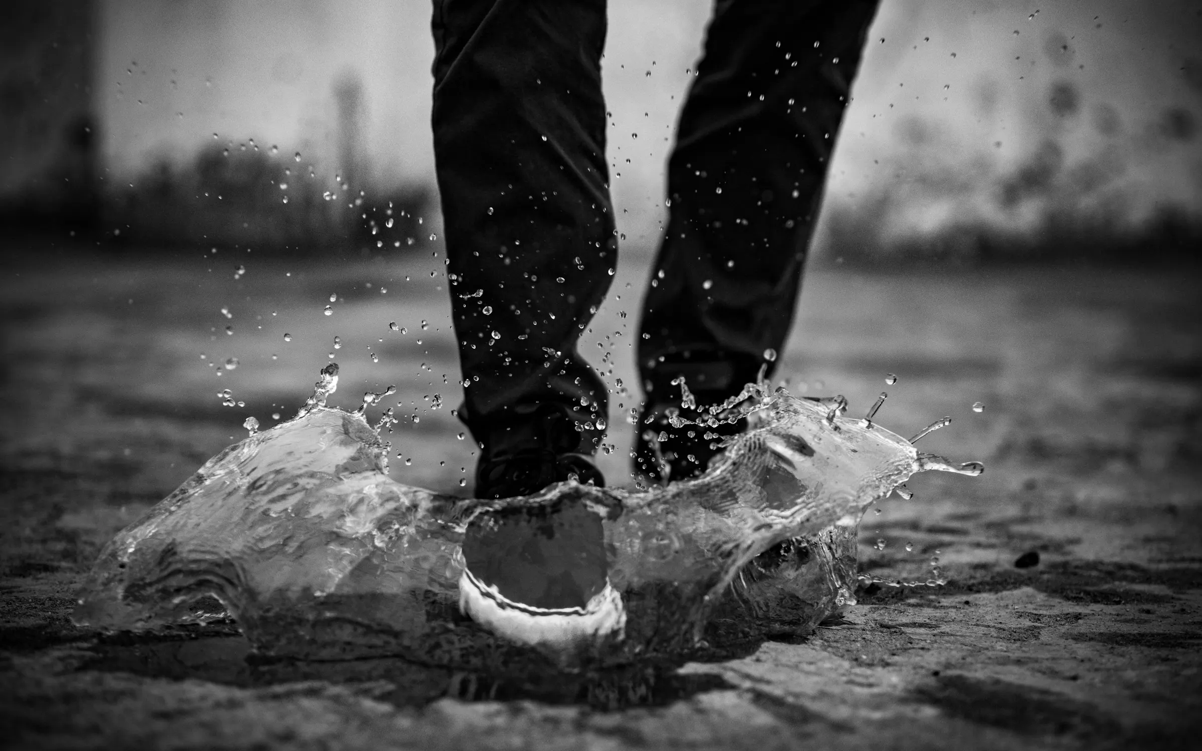 Black and white photo of a sneaker splashing through a puddle