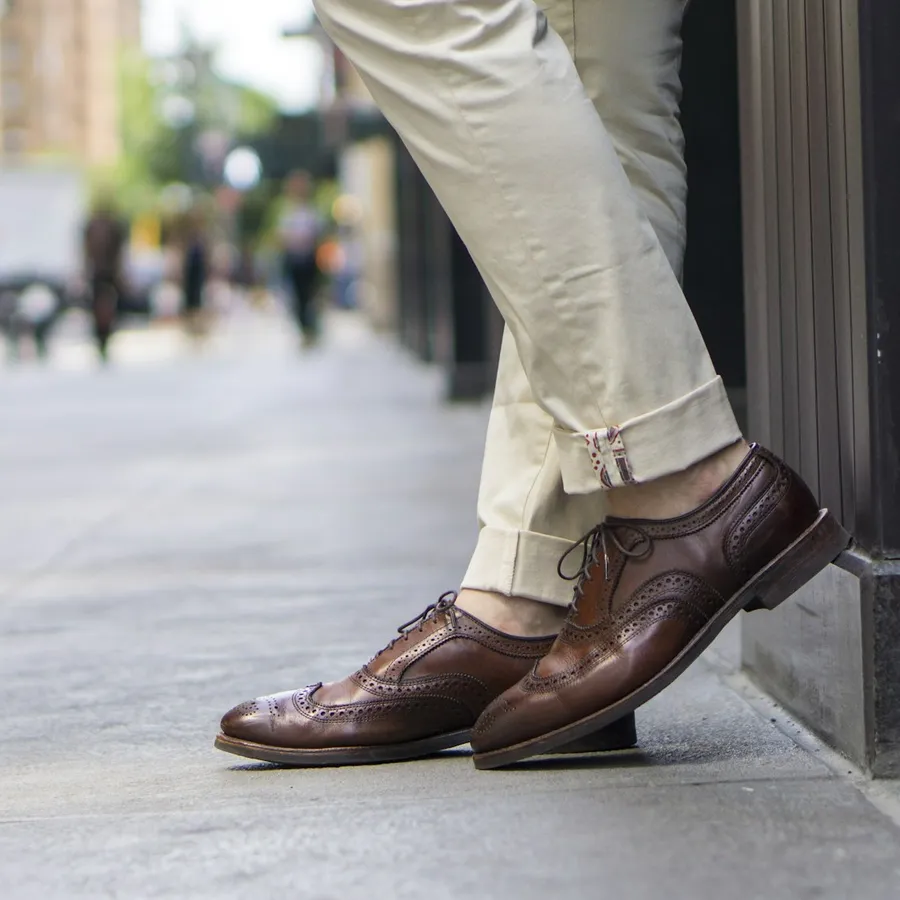 Brown brogues and rolled chinos on a pavement