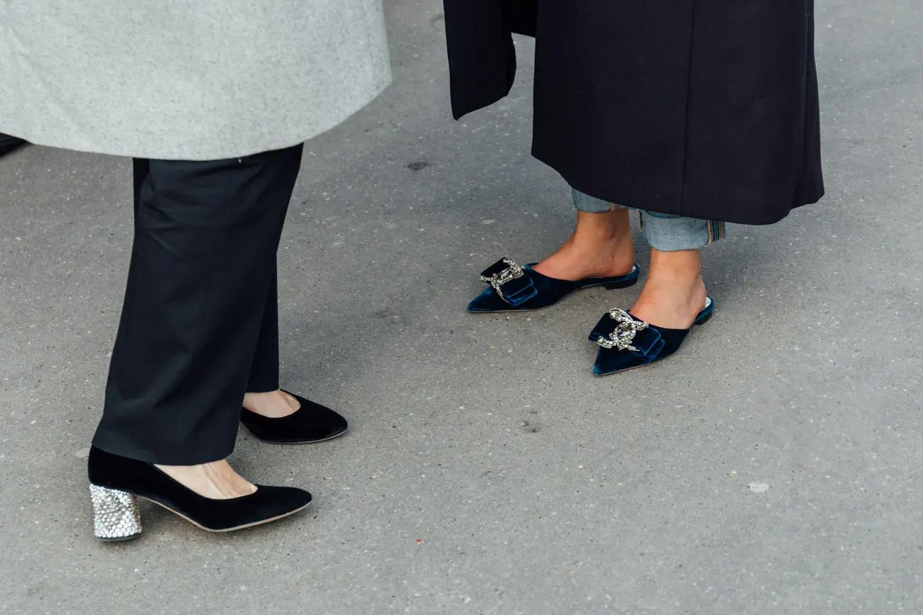 Embellished velvet flats and black heels on a city pavement
