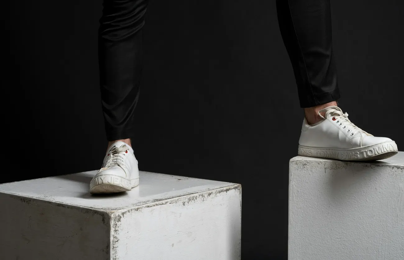 White leather sneakers between two concrete blocks